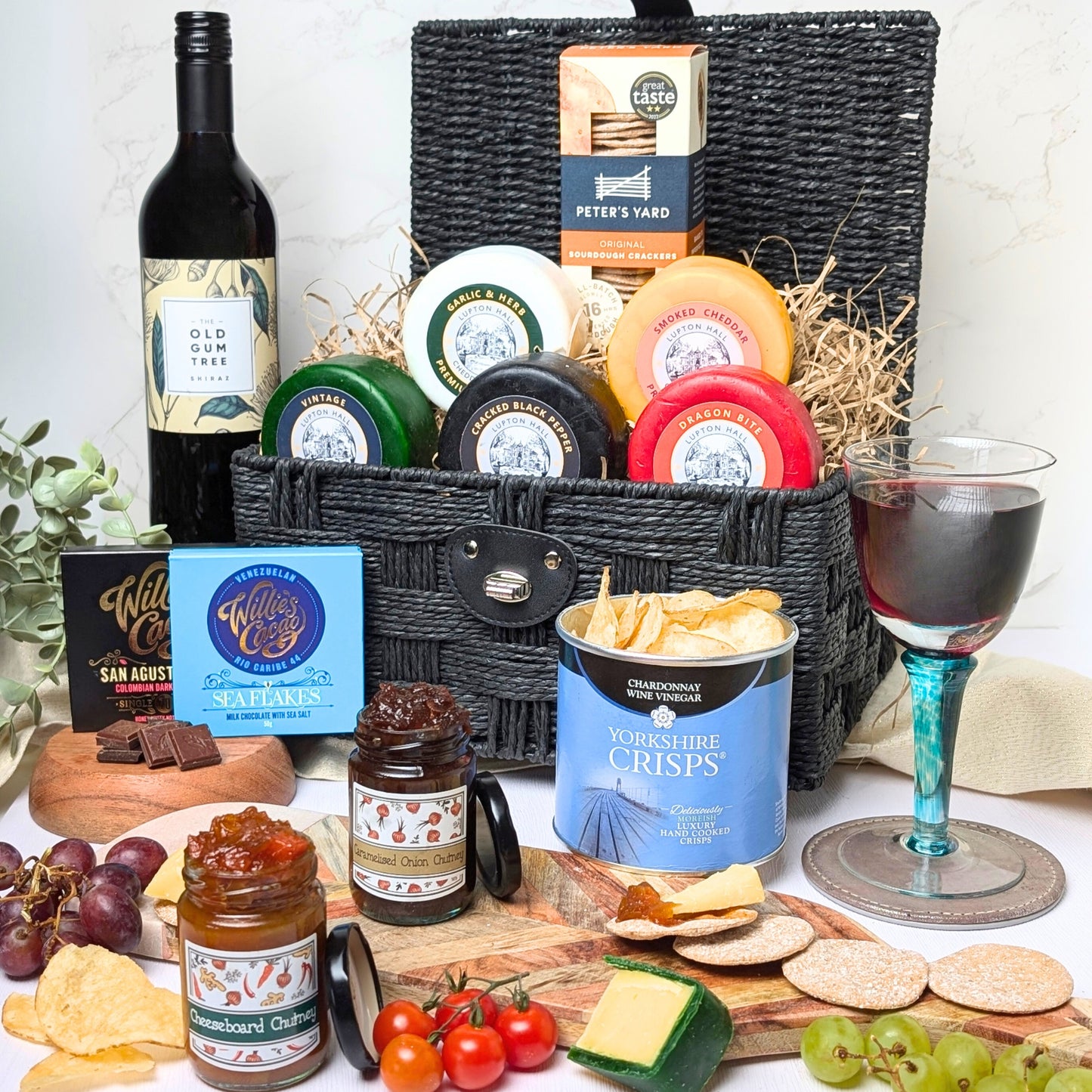 Full display of the 12-item Luxury Cheese & Wine Hamper, showcasing artisan cheeses, chutneys, sourdough crackers, crisps, chocolates, and Old Gum Tree Shiraz (75cl).