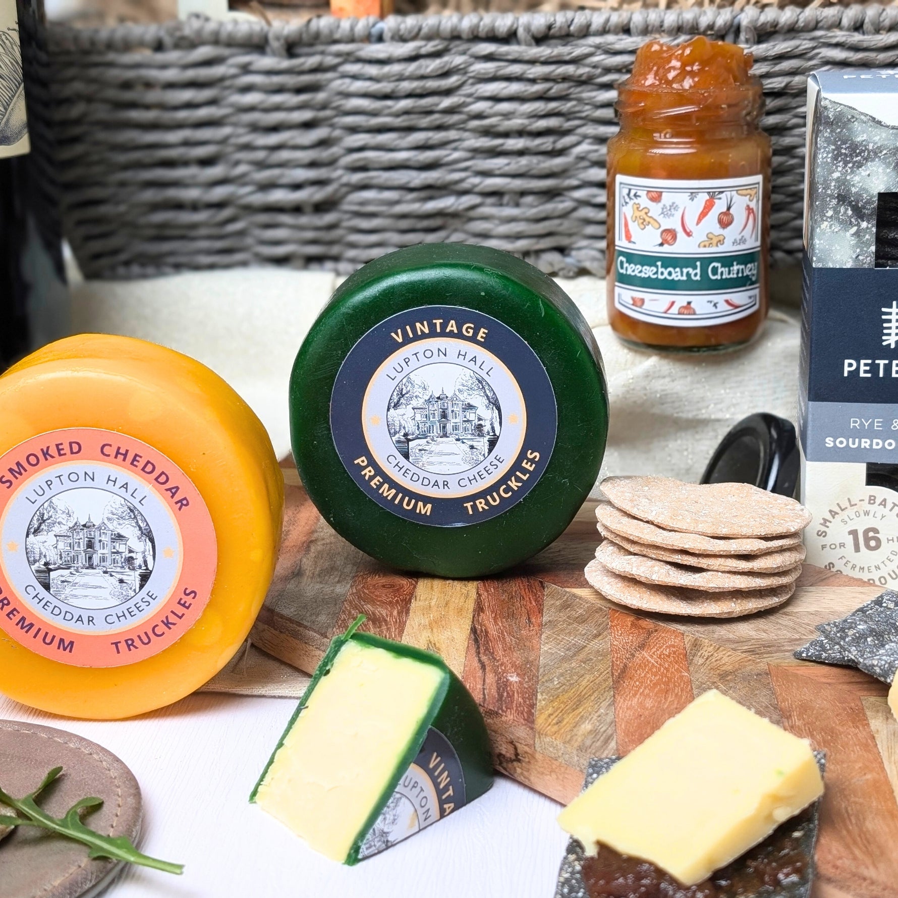 Close-up of two artisan cheese truckles: Vintage Cheddar and Smoked Cheddar, included in the Cheese and Wine Gift Hamper Basket.