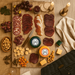 Wooden charcuterie board with cured meats, cheeses, and snacks on a rustic wooden table.