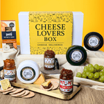 Cheese Gift Box with various cheeses, jams, and crackers on a wooden board against a yellow background.