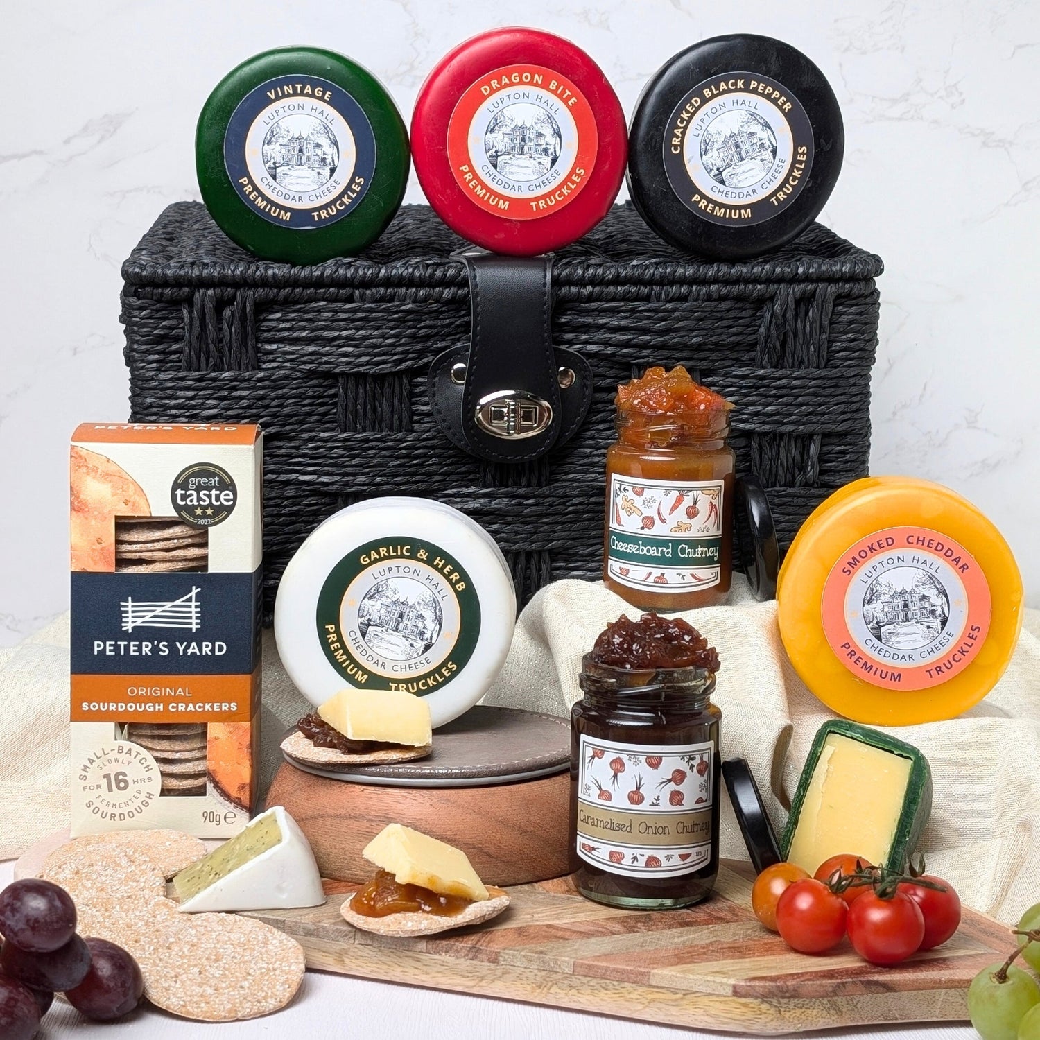 Luxury cheese hamper gift with five truckles, two chutneys, Peters Yard sourdough crackers, and black woven hamper basket.